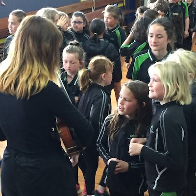A violinist showing children from Martinborough school her instrument