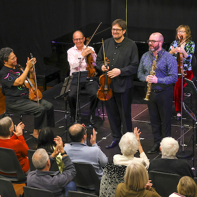 Artists acknowledging applause in Martinborough Ton hall at the end of the 2025 Festival