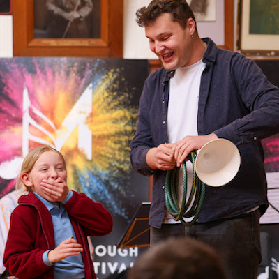 A school girl gasping in surprise at a brass instrument made out of. hose
