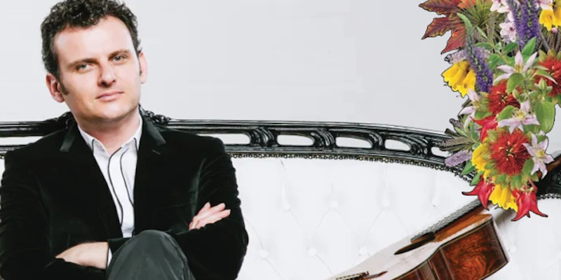 Slava Grigoryan siting on a couch with a guitar beside him