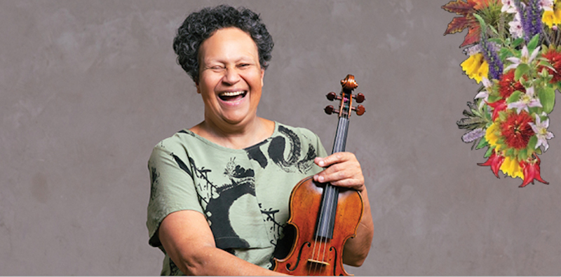 A laughing Wilma Smith holding her violin