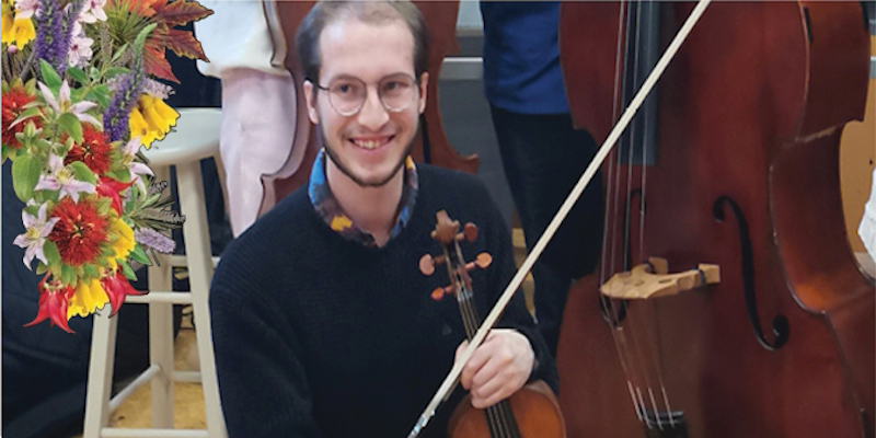 Lucas Baker holding a violin with a double bass in the background
